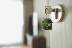 Keychain shaped like a house dangling off a key in a front door lock