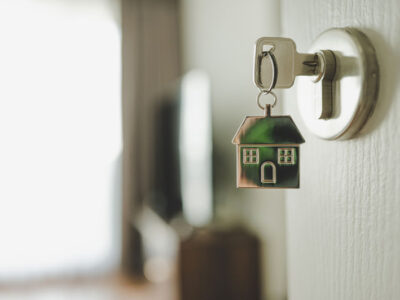 Keychain shaped like a house dangling off a key in a front door lock