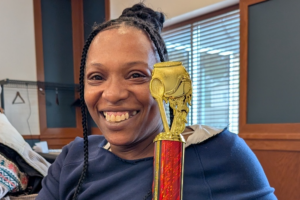Photo of Model Cities staff member, smiling and holding small trophy