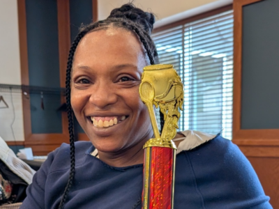 Photo of Model Cities staff member, smiling and holding small trophy