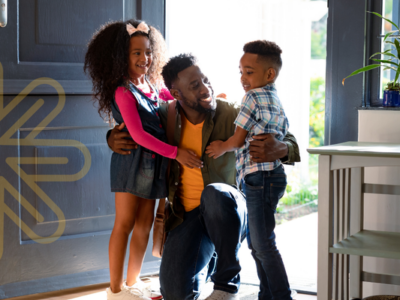 Photo of parent and school age children smiling in the entryway to their home